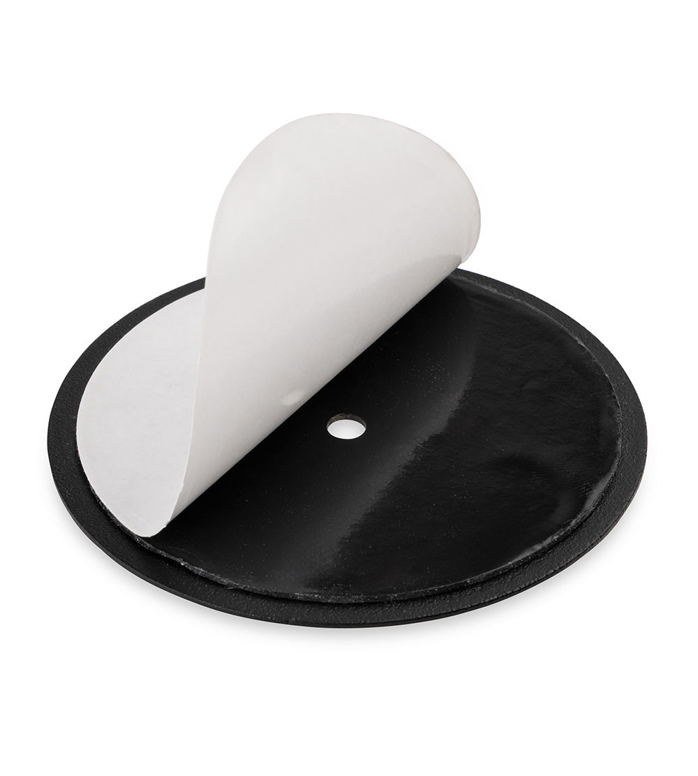 Black circular adhesive pad with a white peel-off backing partially removed