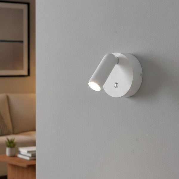 White wall-mounted spotlight with an adjustable head, illuminating a light grey wall