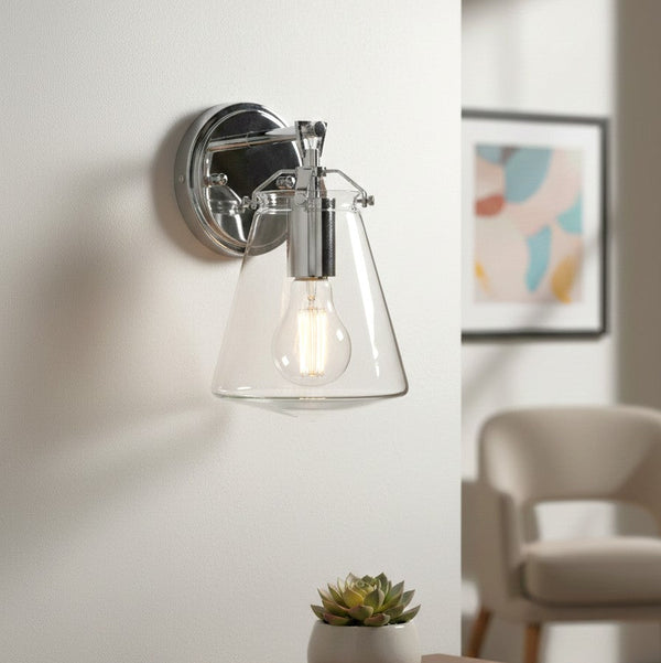 Chrome wall sconce with a clear glass conical shade and an exposed Edison bulb