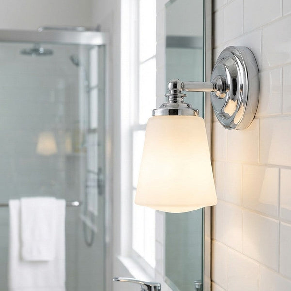 Chrome wall sconce with a white frosted glass shade in a bathroom