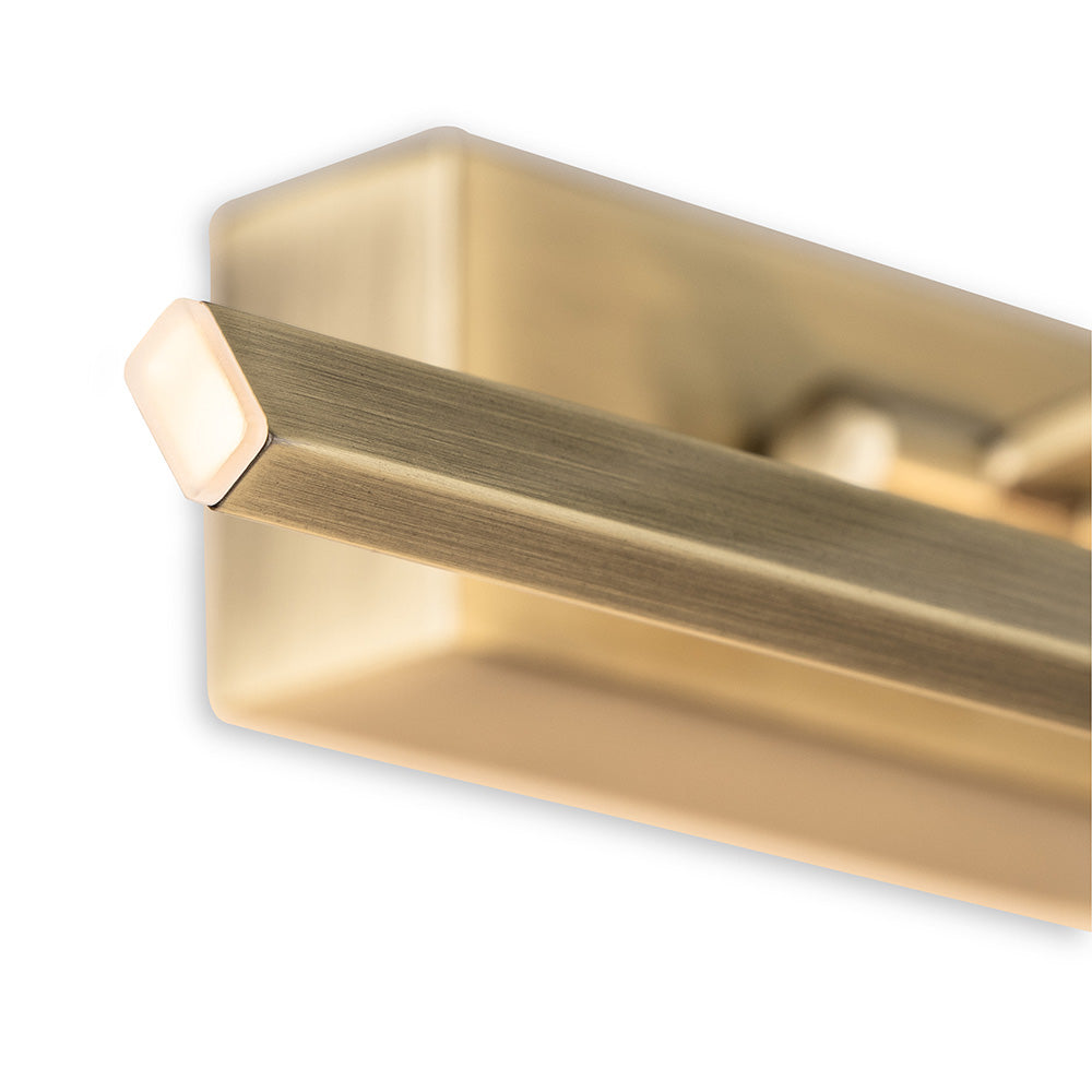 Close up of a brass picture light with a rectangular arm and a glowing light at the end