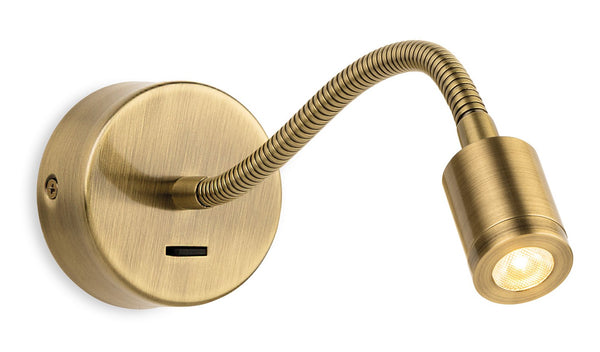 Flexible brass wall light with a round base and a cylindrical head, emitting a warm glow