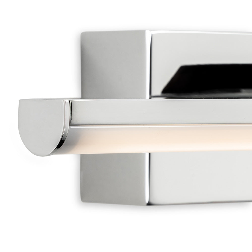 Close-up of a chrome wall-mounted light fixture with a horizontal frosted glass tube emitting a soft glow