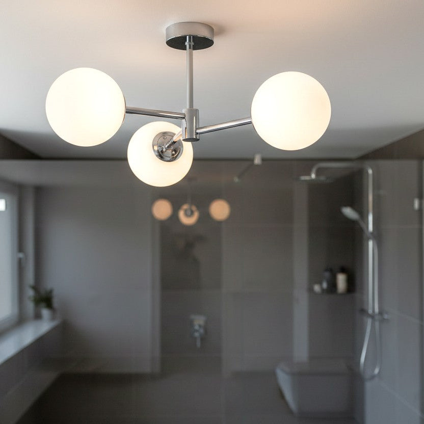 Chrome ceiling light with three spherical white glass shades in a modern bathroom