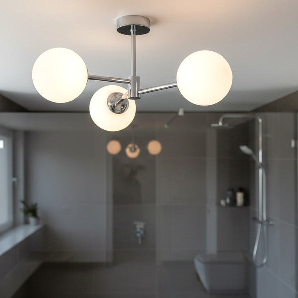 Chrome ceiling light with three spherical white glass shades in a modern bathroom