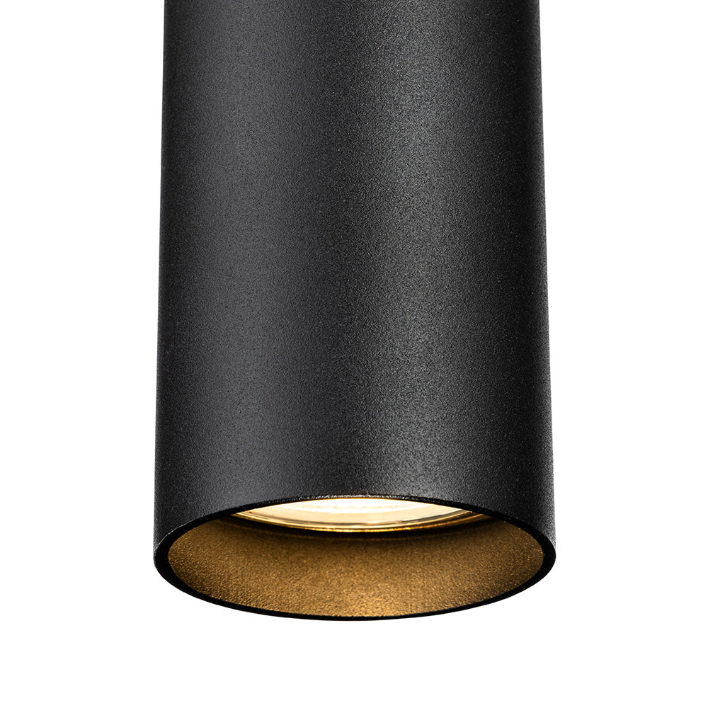 Black cylindrical light fixture with a gold interior and a warm glowing bulb