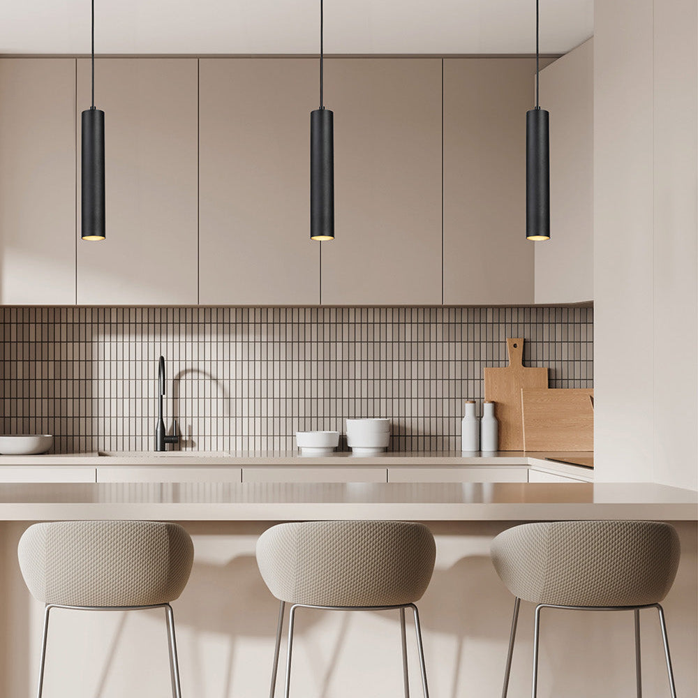Three black cylindrical pendant lights illuminate a modern kitchen island with bar stools