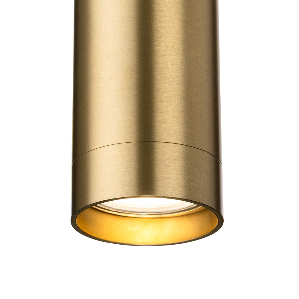 Close up of a brass cylindrical light fixture with a warm glow