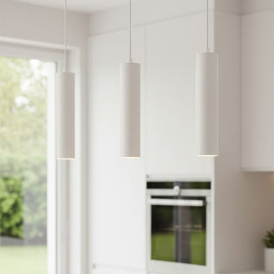 Three white cylindrical pendant lights hanging in a modern kitchen