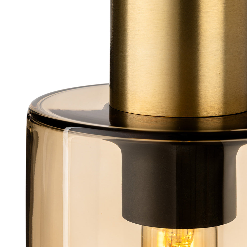 Close up of a brass and glass pendant light with a visible lightbulb