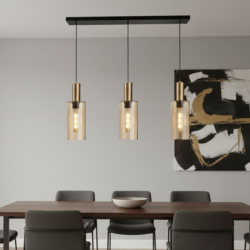 Three pendant lights with brass accents and amber glass shades hanging above a dining table