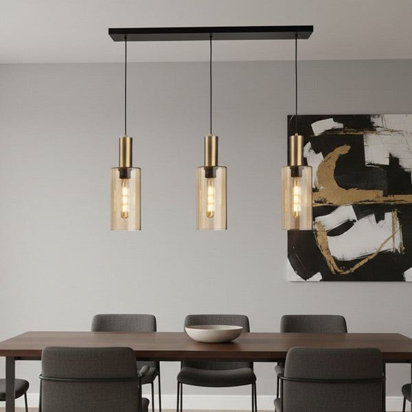 Three pendant lights with brass accents and amber glass shades hanging above a dining table