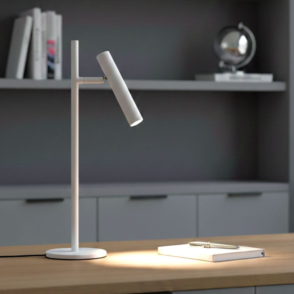 White desk lamp illuminating a notebook and pen on a wooden desk