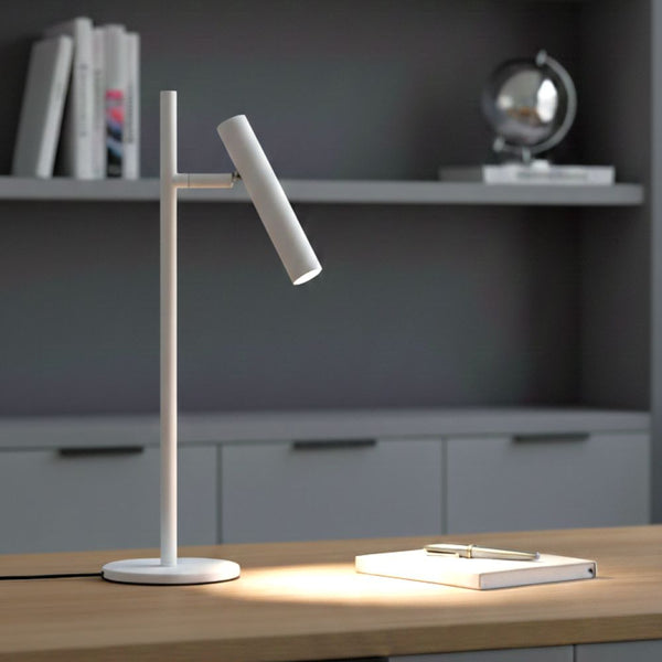 White desk lamp illuminating a notebook and pen on a wooden desk
