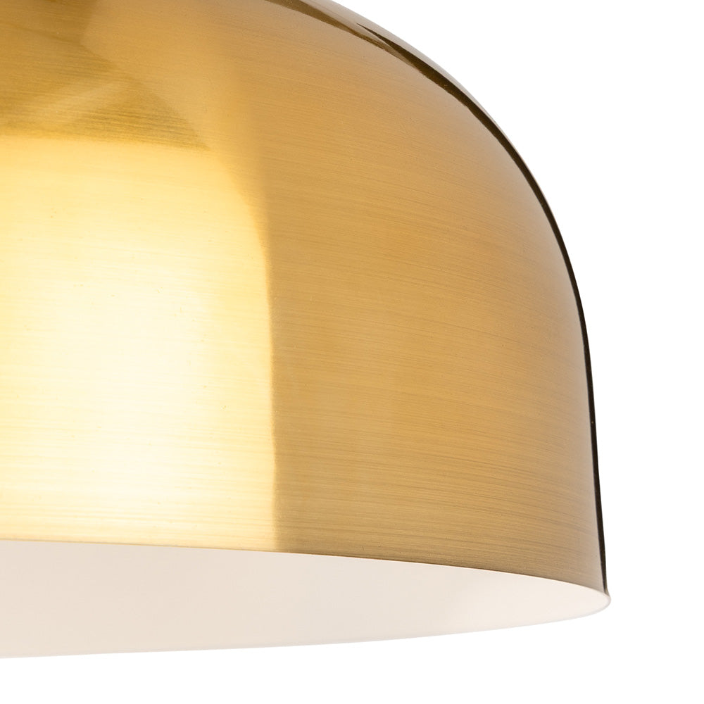 Close up of a brushed brass dome pendant light shade with a white interior