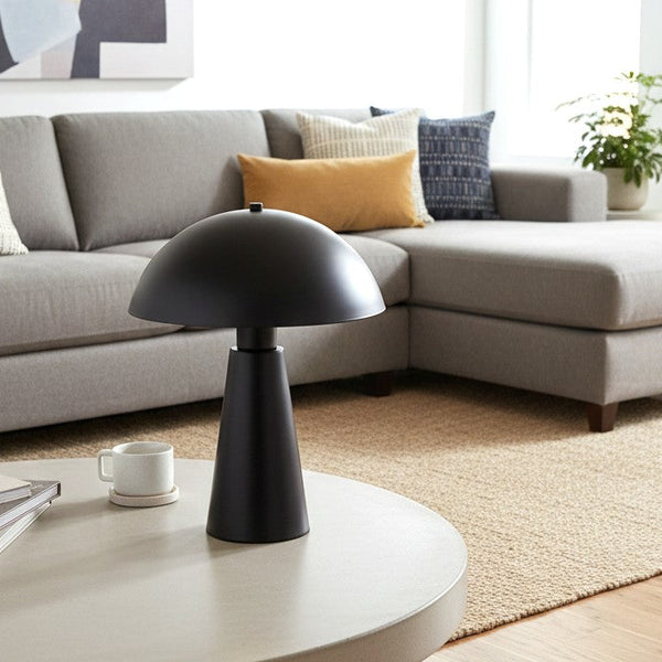 Black mushroom table lamp on a round coffee table in a living room with a grey sectional sofa