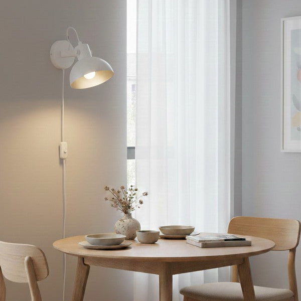 White wall lamp with a light wood dining table and chairs