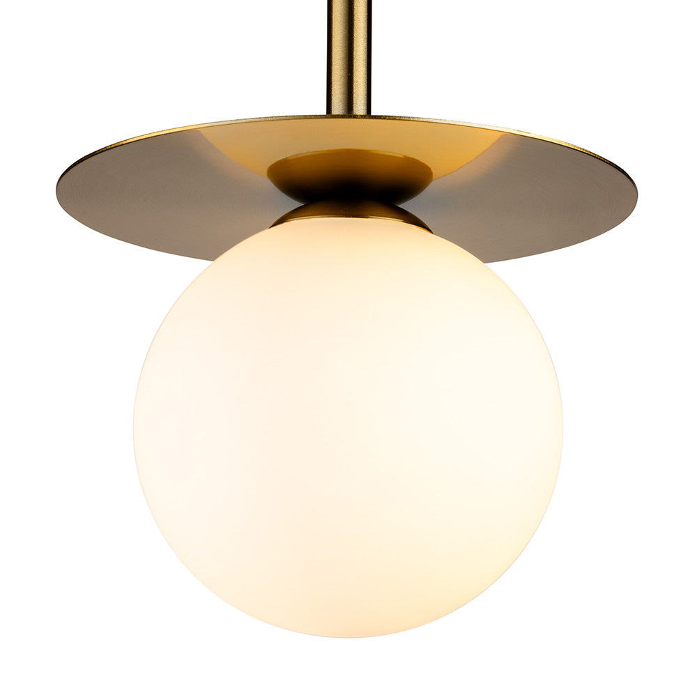 Close up of a brass ceiling light with a round white glass shade