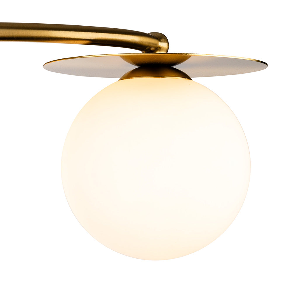 Close up of a brass light fixture with a round white glass shade