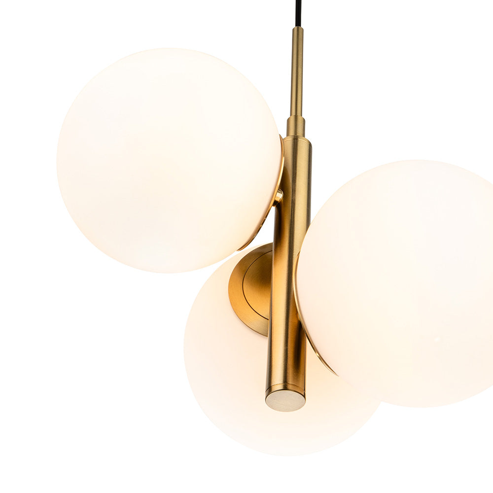 Close up of a brass chandelier with three white globe lights