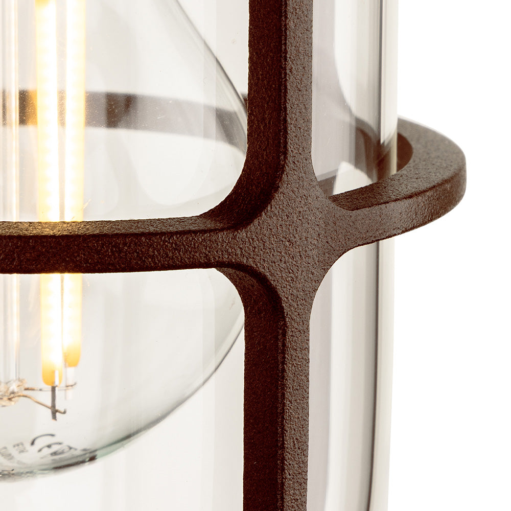 Close up of a light fixture with a clear glass shade and a dark brown metal frame