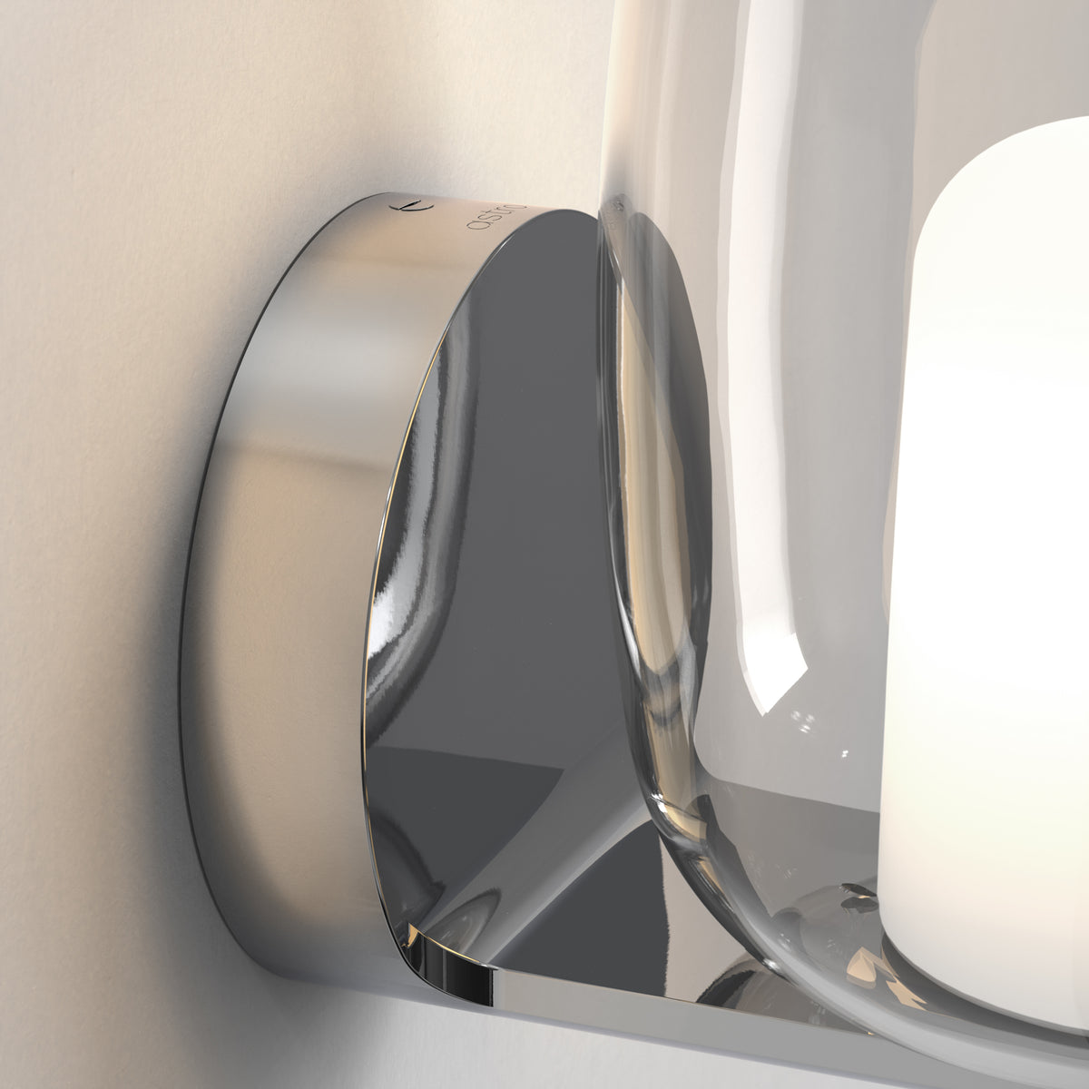 Close up of a chrome wall light with a clear glass shade and a white light source