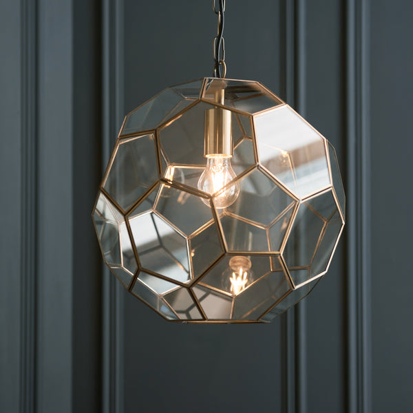 Close-up of a geometric glass and brass pendant light with an exposed bulb.