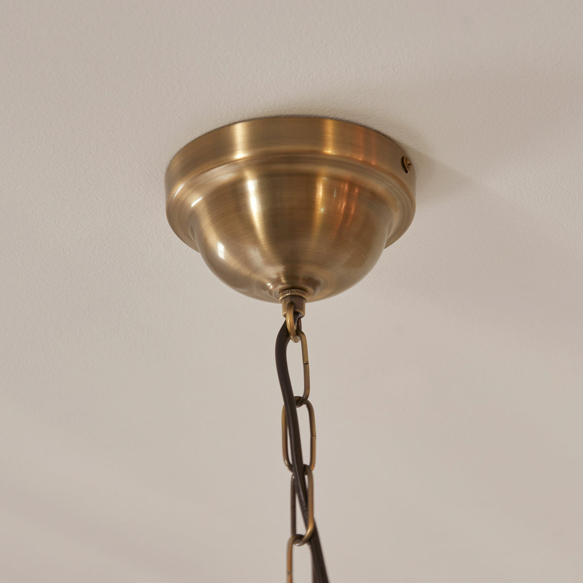 Close-up of a brass ceiling rose and chain for a pendant light.