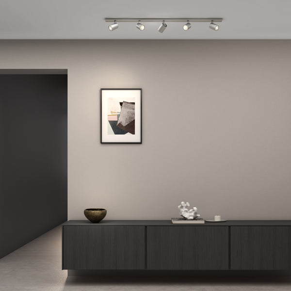 A modern living room with a dark grey media console, abstract art, and a track light with four spotlights