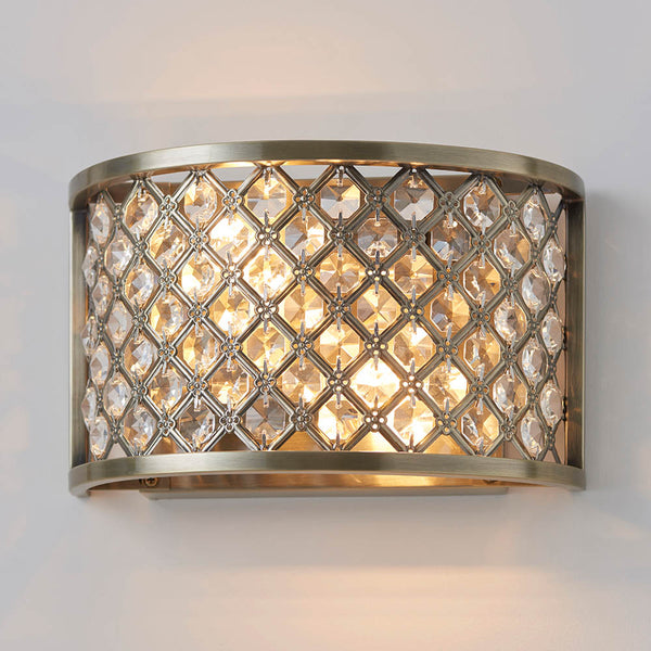 Close-up of a lit antique brass wall light with a decorative crystal grid.