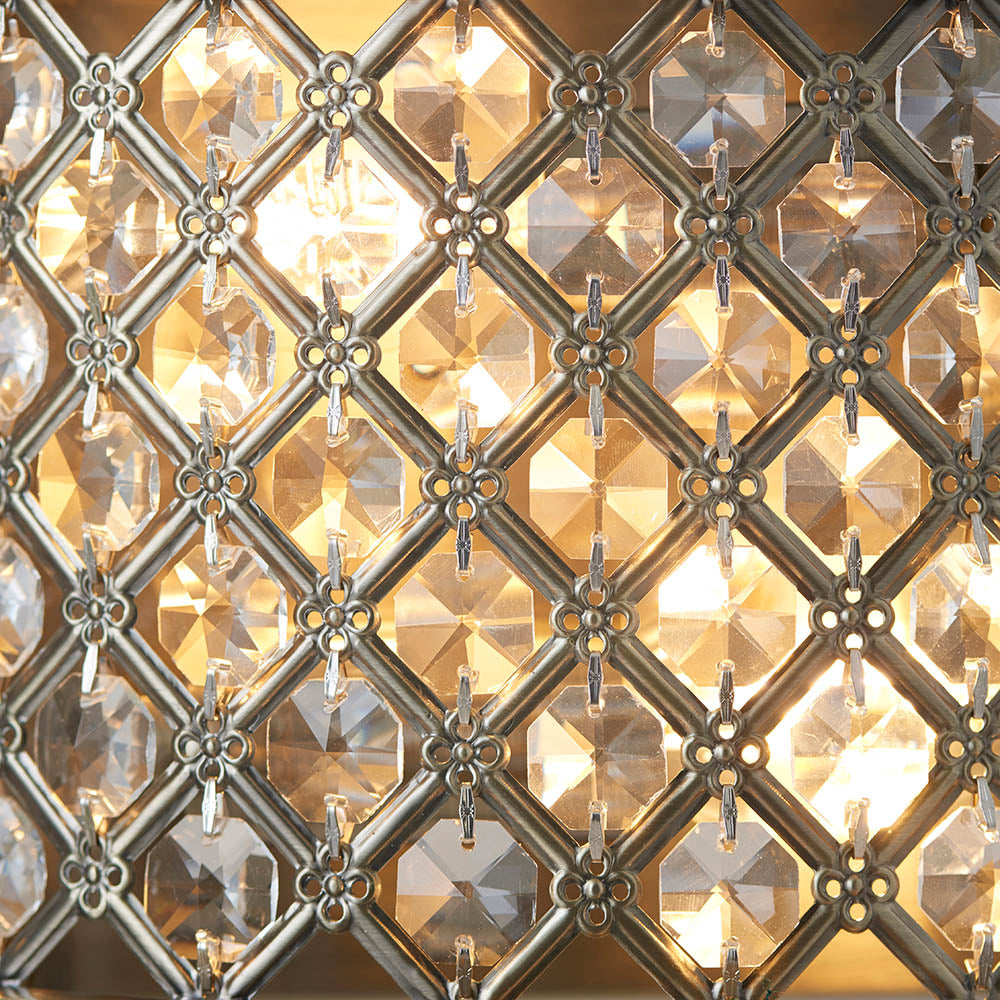 Close-up of the illuminated crystal grid on an antique brass wall light.