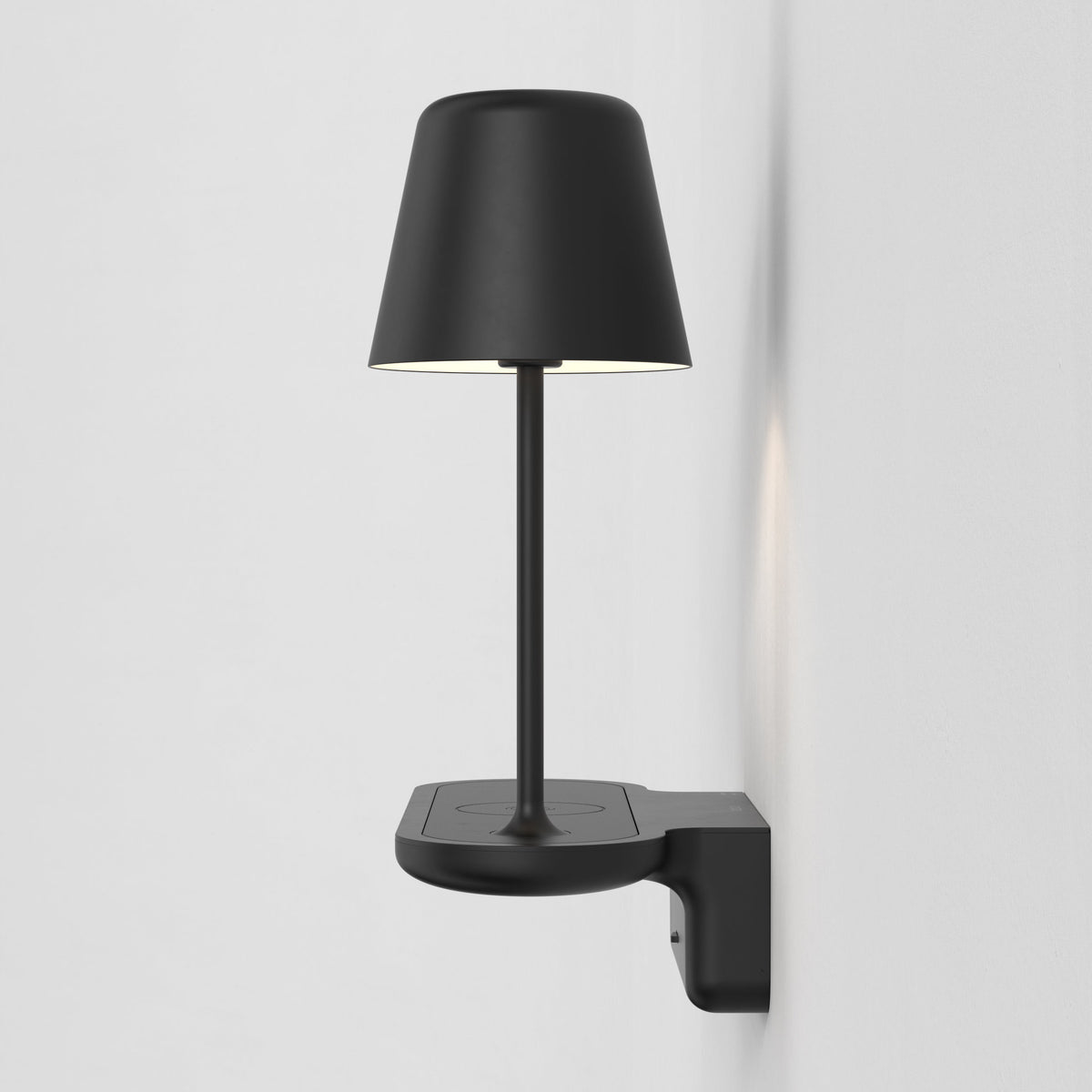 Black wall-mounted lamp with a conical shade and a circular base, providing both upward and downward light