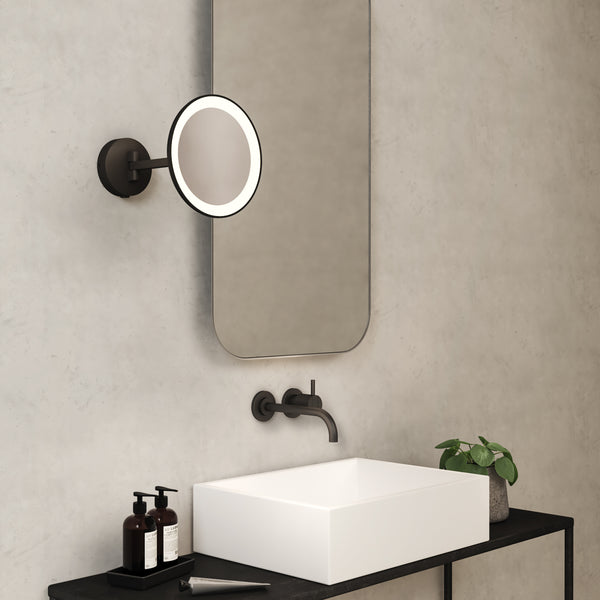 Bathroom vanity with a white rectangular sink, black faucet, and a round illuminated mirror