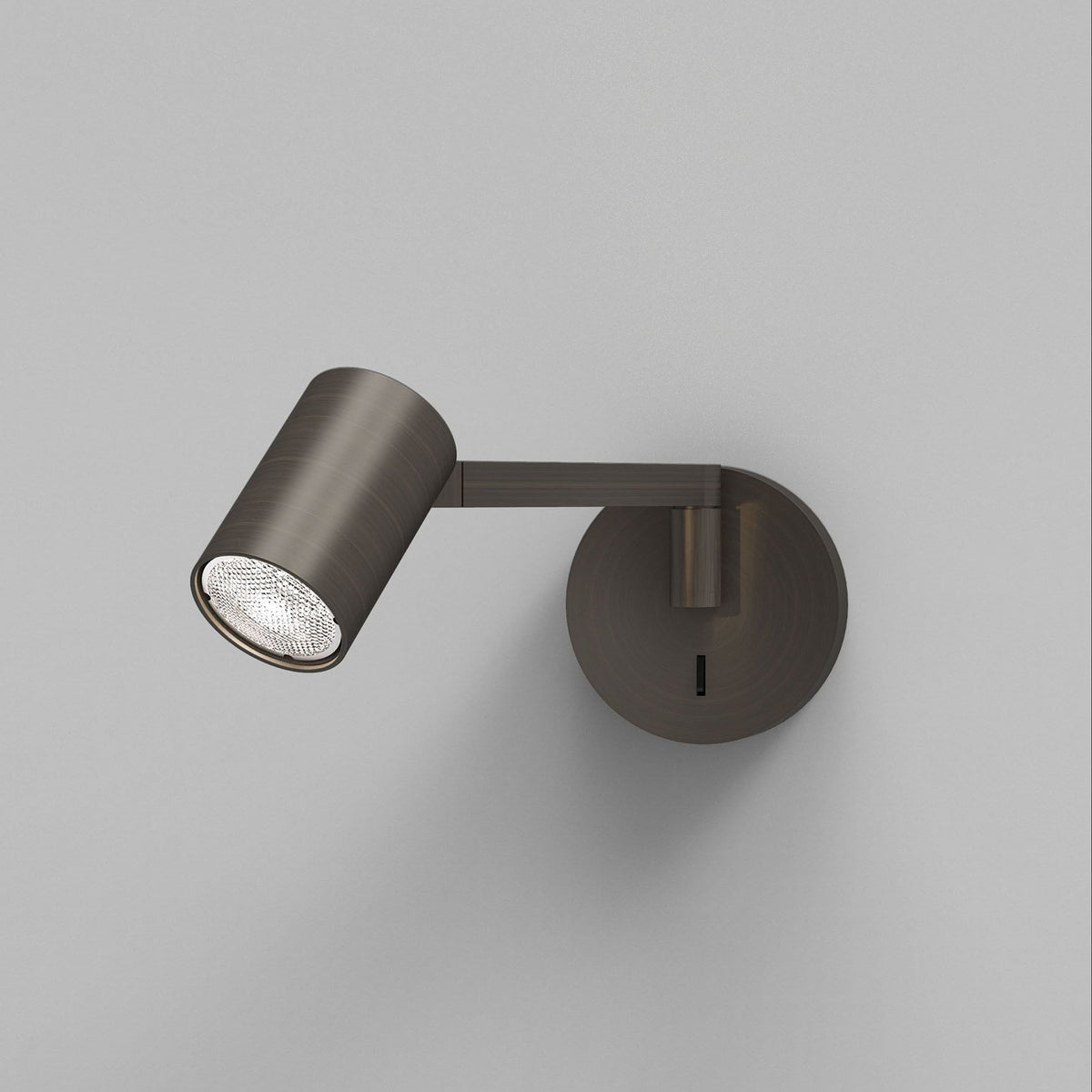 Bronze wall-mounted spotlight with a circular base and an adjustable arm, casting light downwards