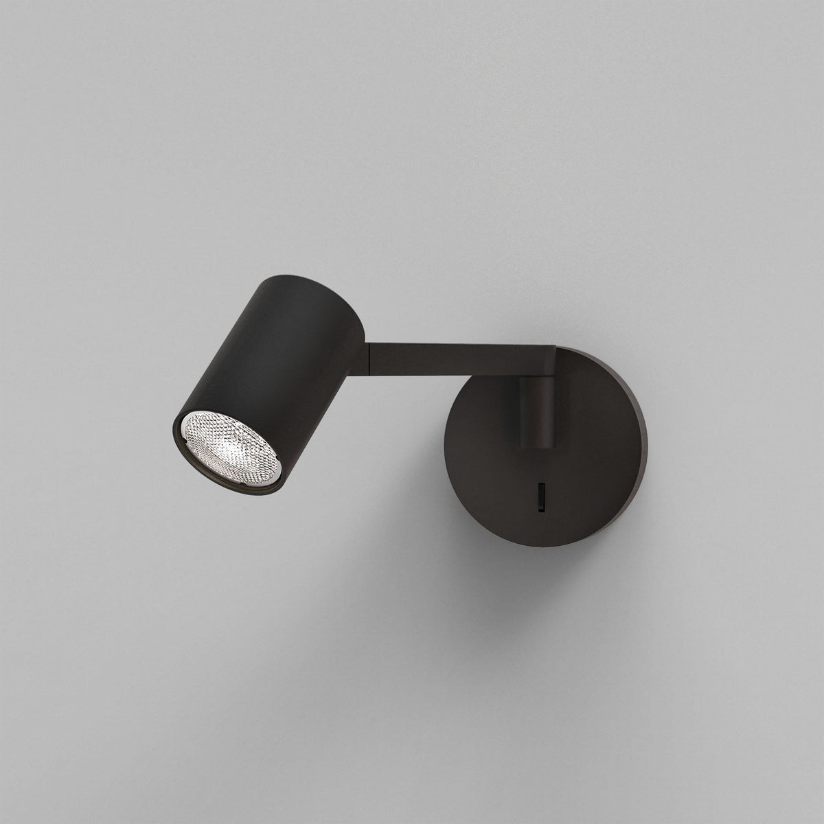 Black wall-mounted spotlight with a textured silver bulb, angled downwards and to the left