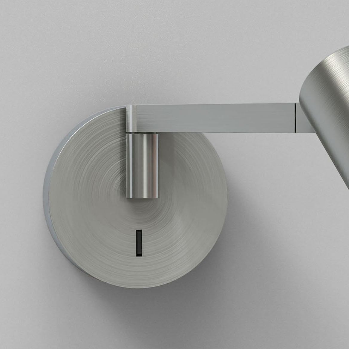 Close up of a brushed metal wall light fixture with a circular base and a rectangular arm