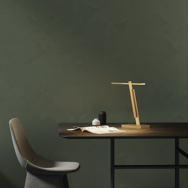 Desk with a wooden lamp, two vases, and an open magazine, next to a grey chair
