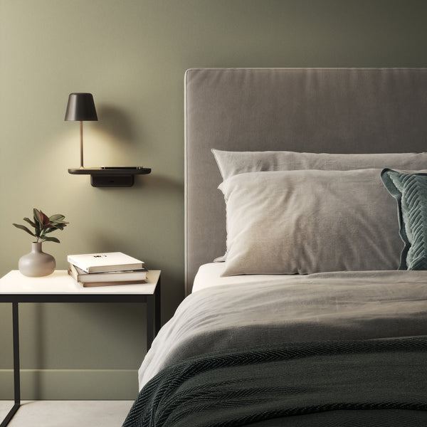 Bedroom with green walls, a grey upholstered headboard, and a side table with books and a vase