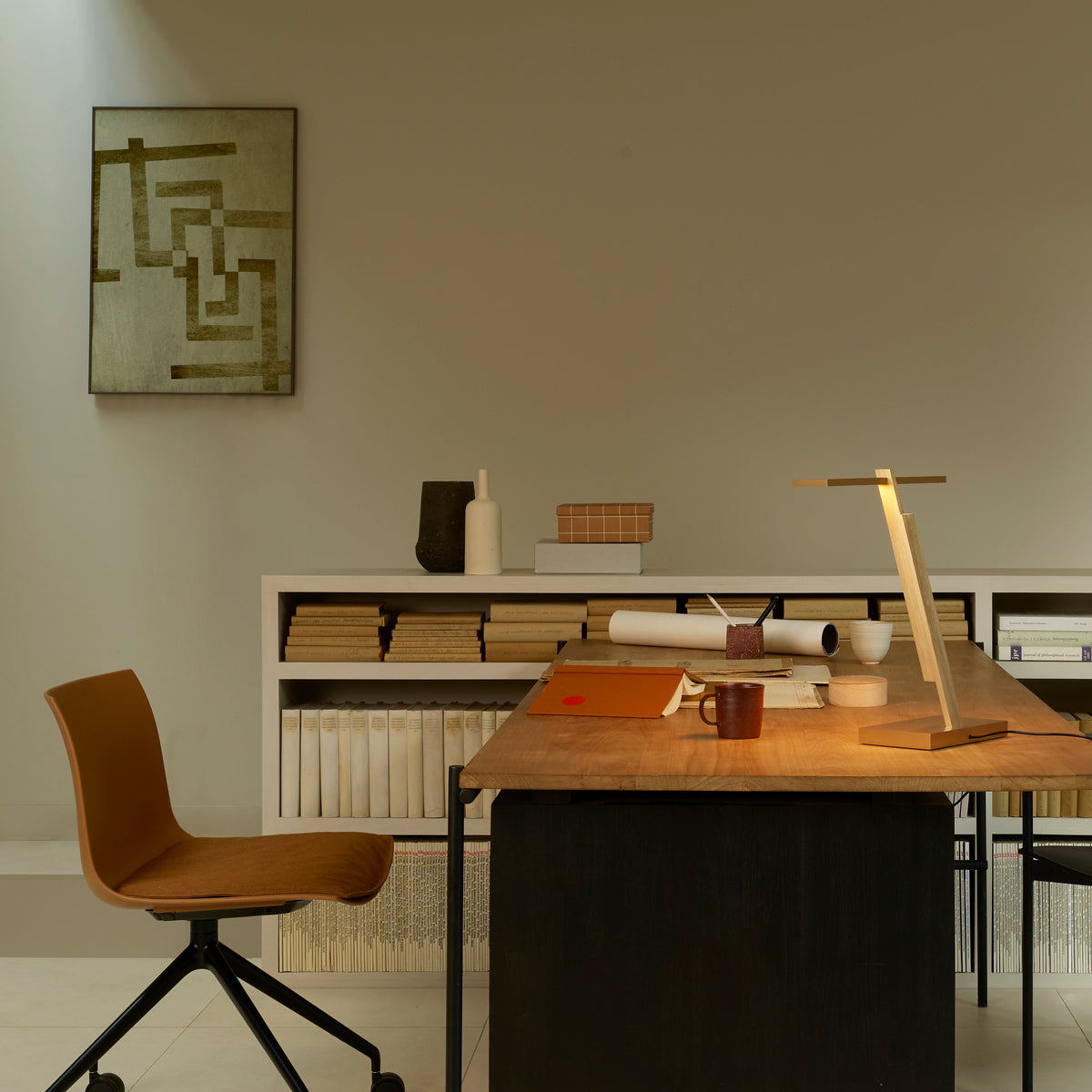 Home office with a wooden desk, an orange chair, and a bookshelf filled with books