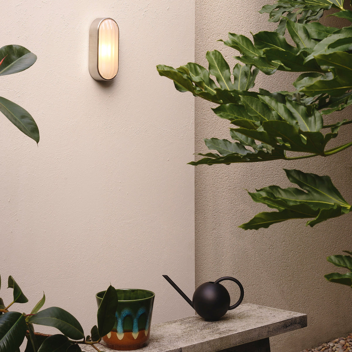 Astro Montreal Oval IP44 Exterior Wall Light in Brushed Stainless Steel on a textured wall