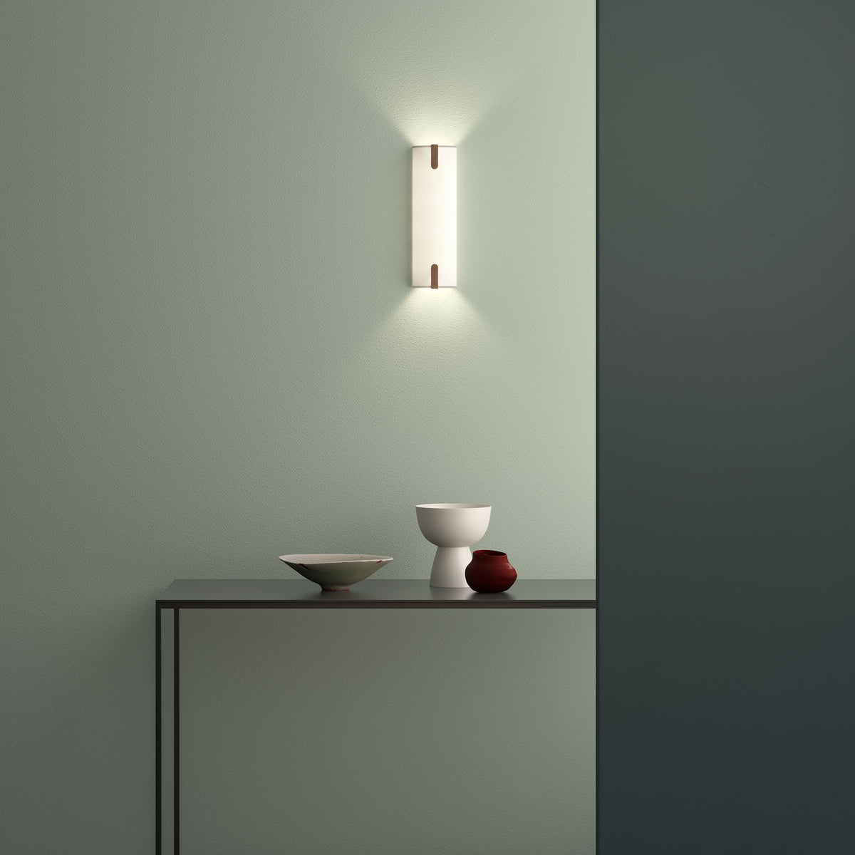 Wall sconce with a rectangular white shade and a brown accent, mounted on a light green textured wall