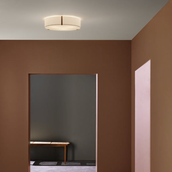 A ceiling light fixture with a white fabric shade and wooden accents illuminates a brown hallway