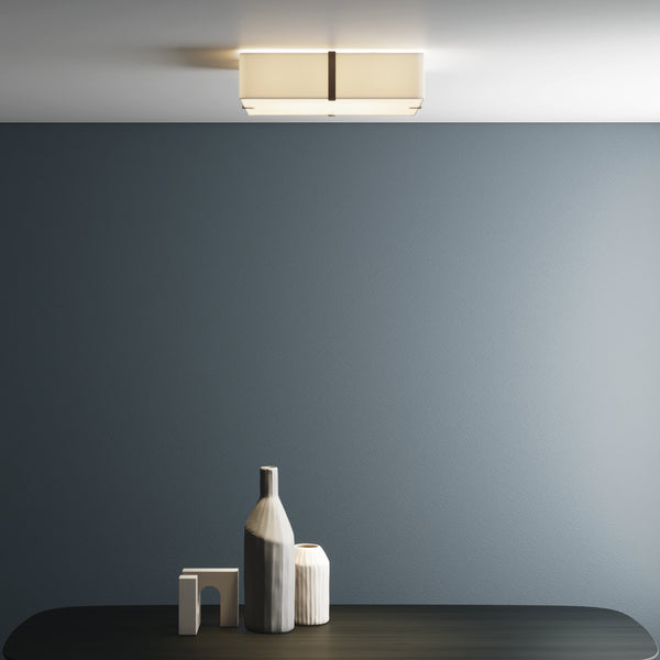 Rectangular ceiling light with a fabric shade and dark metal band, illuminating a dark blue wall and table