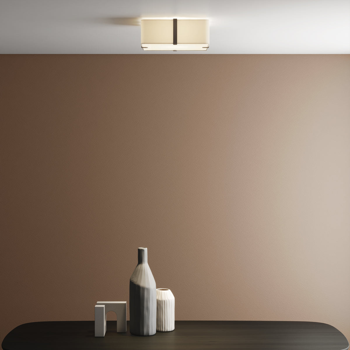Rectangular ceiling light with a fabric shade and dark metal accents, illuminating a brown wall above a dark table