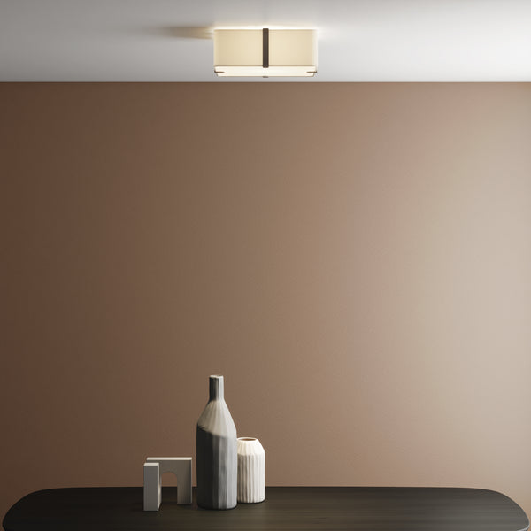 Rectangular ceiling light with a fabric shade and dark metal accents, illuminating a brown wall above a dark table