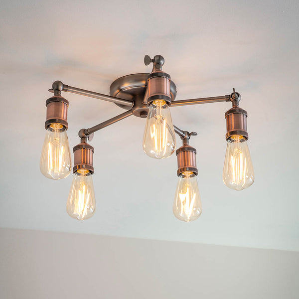 A close-up of a five-light semi-flush ceiling light with exposed bulbs and a bronze finish.