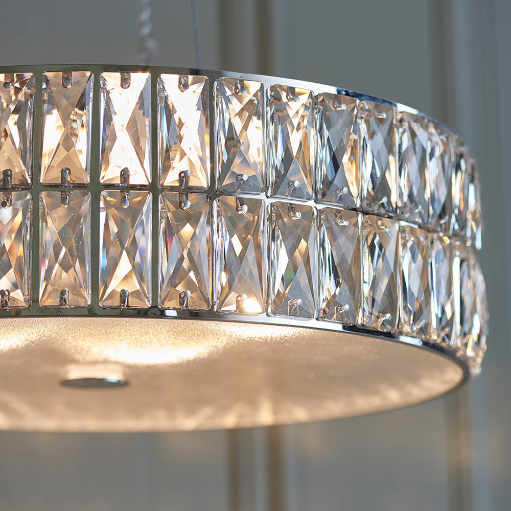 A close-up of the illuminated crystal chandelier, showing the light reflecting off the faceted crystals.
