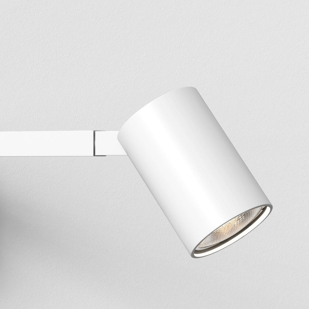 White cylindrical spotlight attached to a white track on a white wall
