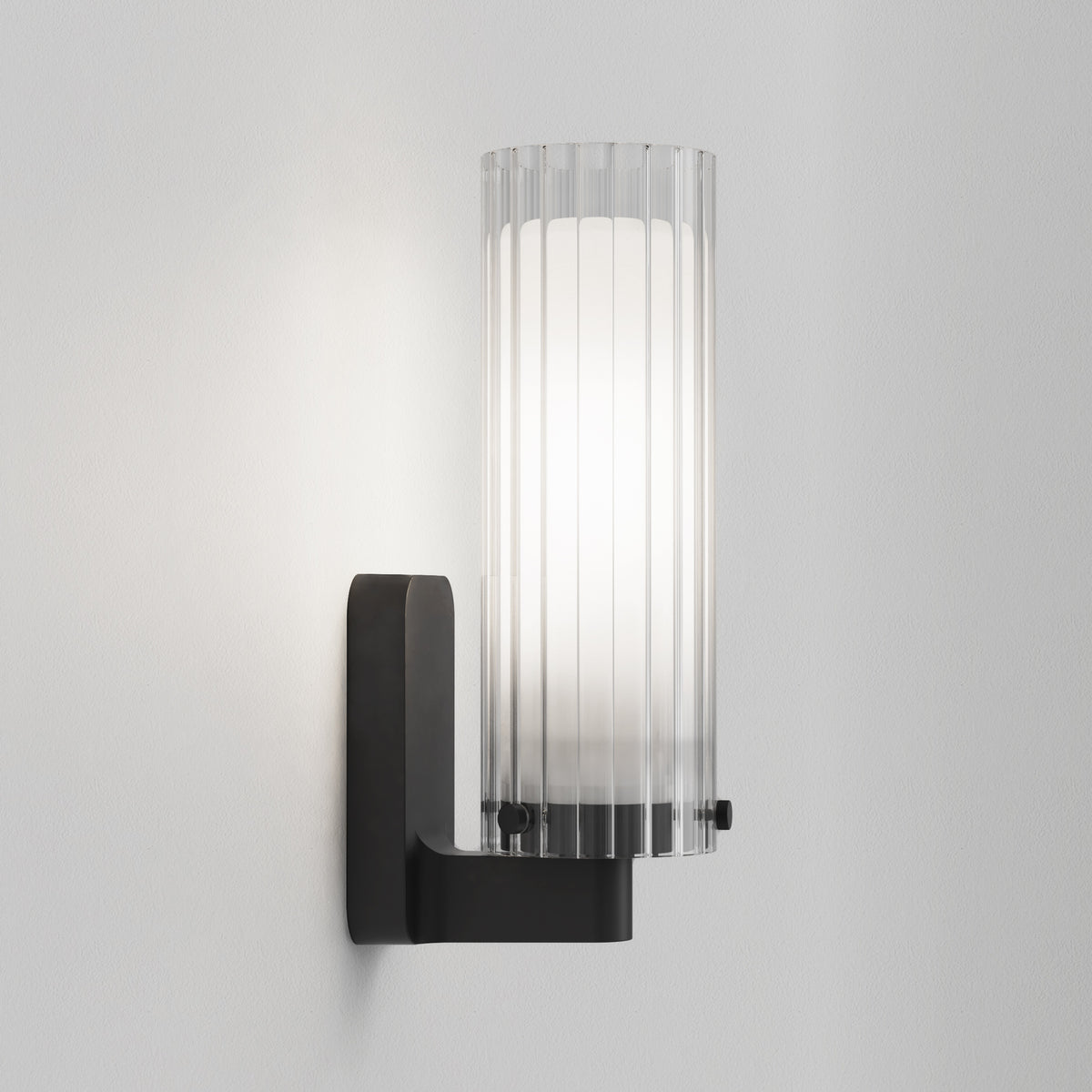 Black wall sconce with a ribbed glass shade and an inner white diffuser
