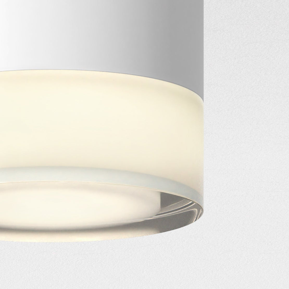 Close up of a white cylindrical light fixture with a glowing bottom edge